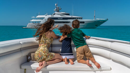 Charter yacht guests observing the motor yacht for charter STARSHIP. A family enjoying the water toys on a family yacht charter. Family yacht charters offer parallel adventures that foster connection, independence, and fun for the whole family.