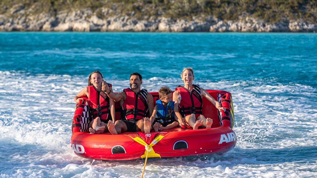 A family enjoying the water toys on a family yacht charter. Family yacht charters offer parallel adventures that foster connection, independence, and fun for the whole family.