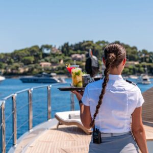 Stewardess serving a drink aboard DB9, a 171 foot Palmer Johnson yacht for charter in the Mediterranean.