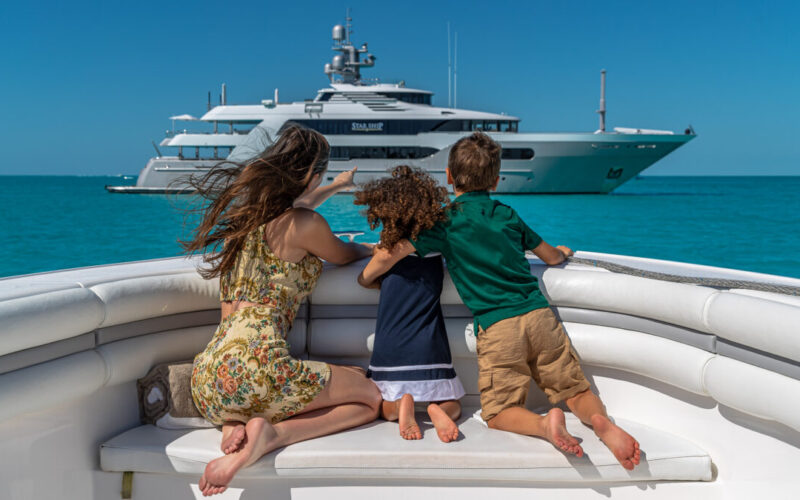 Charter yacht guests observing the motor yacht for charter STARSHIP. A family enjoying the water toys on a family yacht charter. Family yacht charters offer parallel adventures that foster connection, independence, and fun for the whole family.