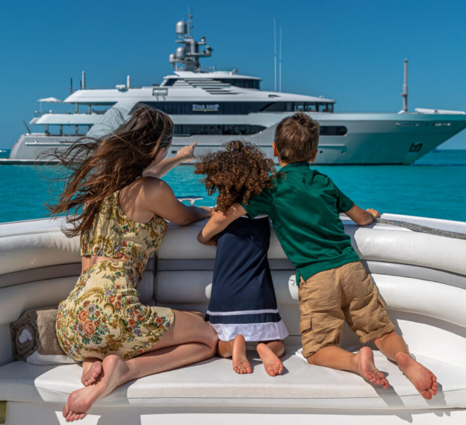 Charter yacht guests observing the motor yacht for charter STARSHIP. A family enjoying the water toys on a family yacht charter. Family yacht charters offer parallel adventures that foster connection, independence, and fun for the whole family.