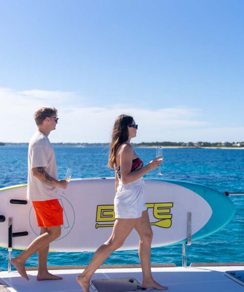 Guests with a paddle board on PLAYTIME, a 64 foot Lagoon yacht for charter in The Bahamas. Guests with a paddle board on PLAYTIME, a 64 foot Lagoon yacht for charter in The Bahamas.